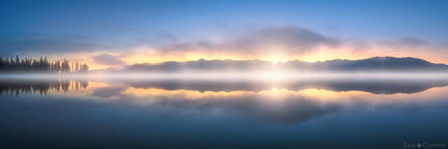 Predawn skies glow on a tranquil morning on Seeley Lake, in western Montana, as mist gently rises from the water