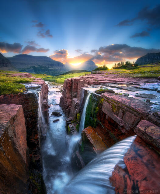 Sun rays at sunrise over waterfall, Glacier National Park, Montana