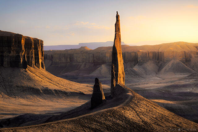 A sandstone tower rising above the badlands of central Utah at sunset