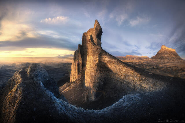 A sandstone spire rising above badlands in central Utah at sunrise