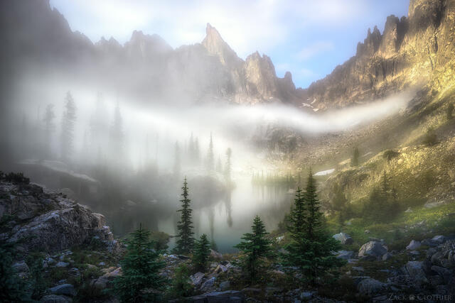 Foggy summer morning in remote alpine cirque in the Idaho Rocky Mountains at sunrise