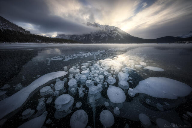Methane bubbles encased in the ice of Lake Minnewanka, in the Canadian Rockies in Banff National Park, at sunrise.
